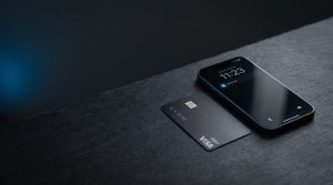 Modern smartphone on a dark desk next to a matte payment card