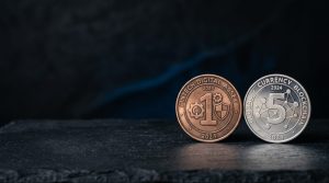 Two physical coins of different colours side-by-side on a neutral dark surface