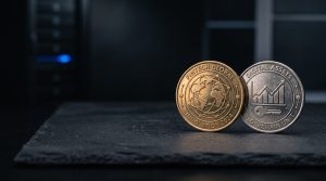 Two physical coins side-by-side on a dark surface: one with Bitcoin symbol, one with XRP symbol