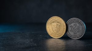 Two physical coins of different colours side-by-side on a neutral dark surface