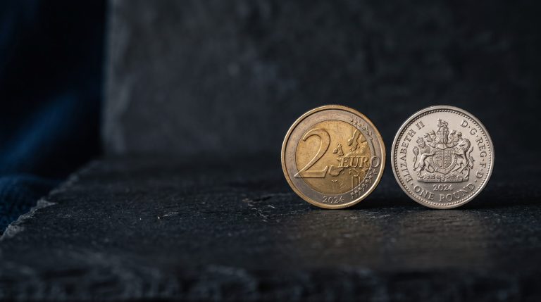 Two physical coins of different colours side-by-side on a neutral dark surface
