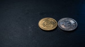 Two physical coins side-by-side on a dark surface—Ethereum with engraved Ξ symbol and XRP with wave motif