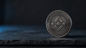 A physical coin engraved with the BNB symbol on a neutral dark surface