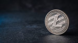 A physical silver coin engraved with the Litecoin symbol