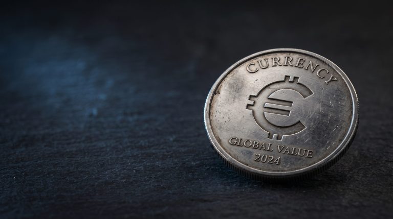 A physical silver coin engraved with the Sui blockchain symbol on a neutral dark surface