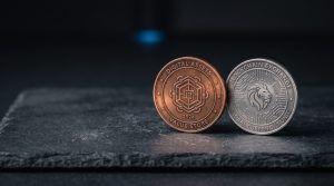 Two physical coins of different colours side-by-side on a neutral dark surface